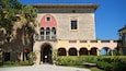 A historic building with a red facade, stone arches, and a balcony.