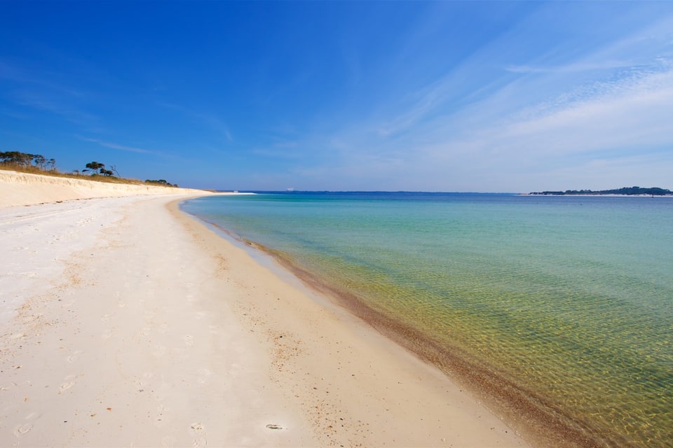 Una playa con aguas poco profundas y cristalinas y una orilla arenosa.