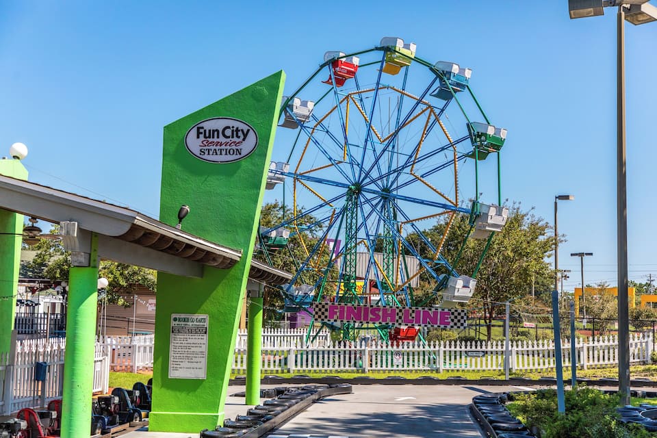 A Ferris wheel at a Fun City amusement park with a green entrance and a 'Finish Line' sign.