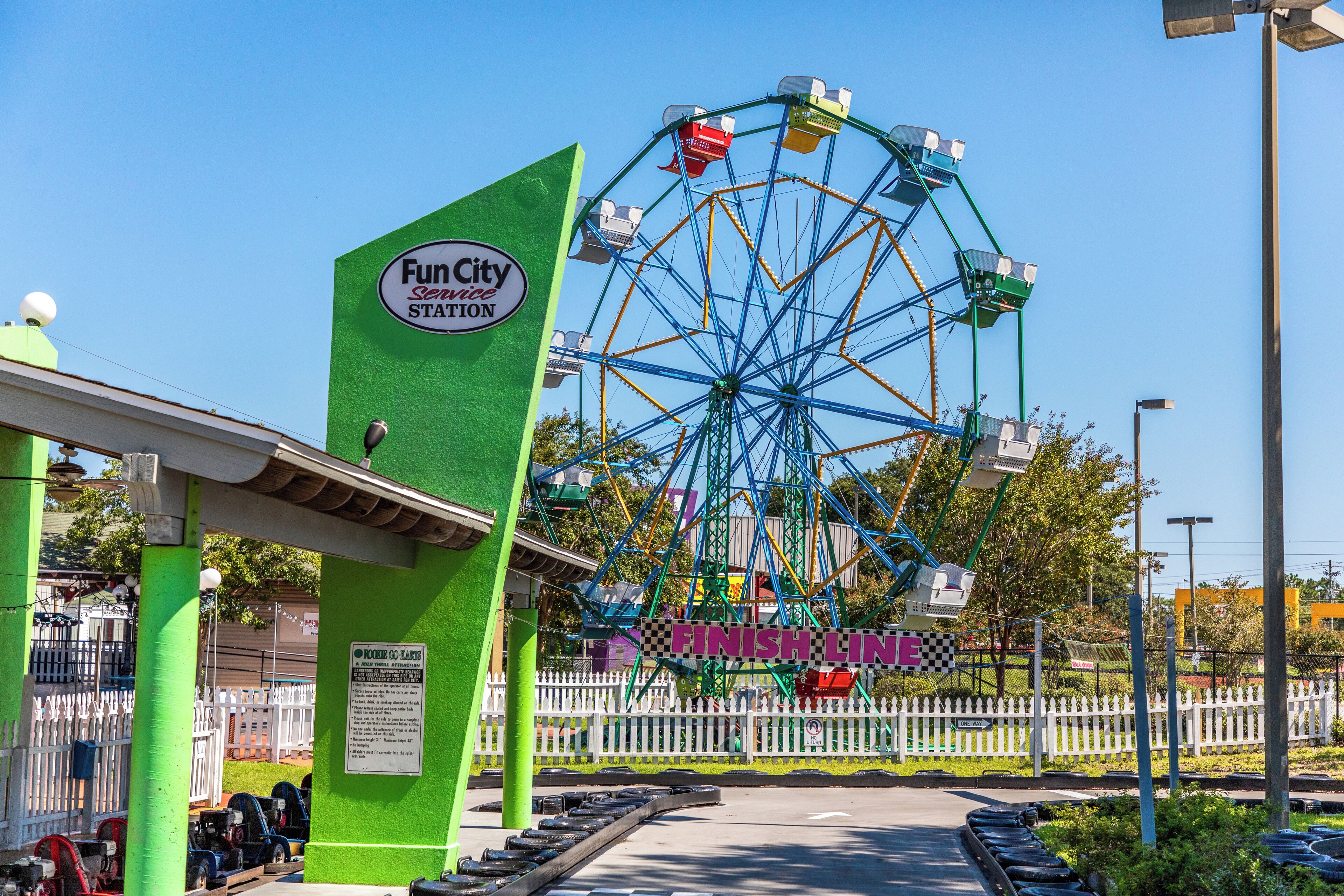 A Ferris wheel at a Fun City amusement park with a green entrance and a 'Finish Line' sign.
