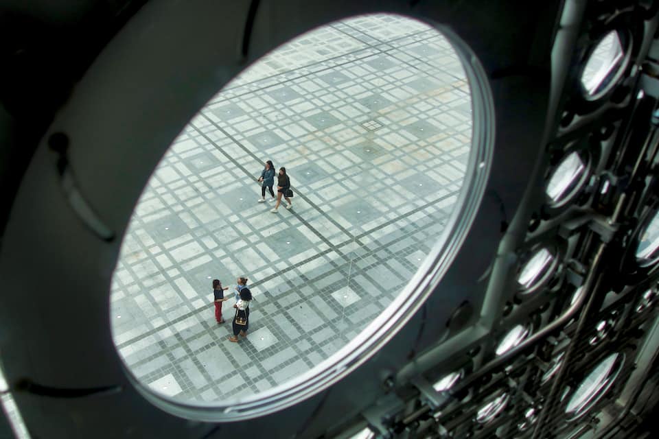 Ein Rundblick auf ein Atrium mit Glasverkleidung, durch das Menschen gehen.