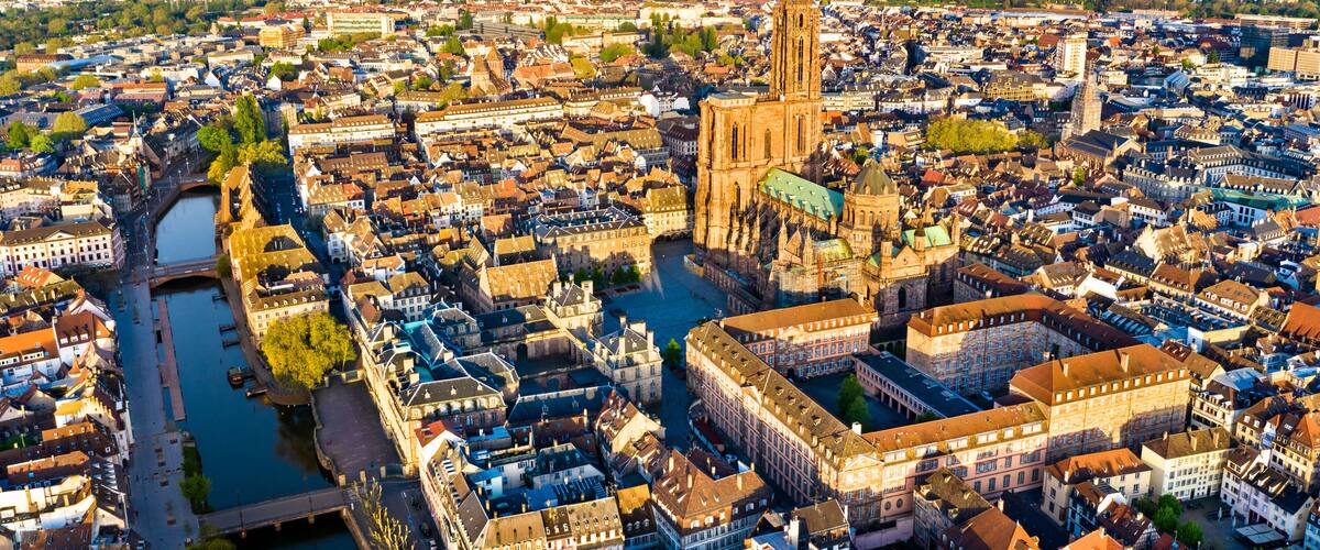 A panoramic view of a historic city with a prominent cathedral, a river, and surrounding dense urban architecture.