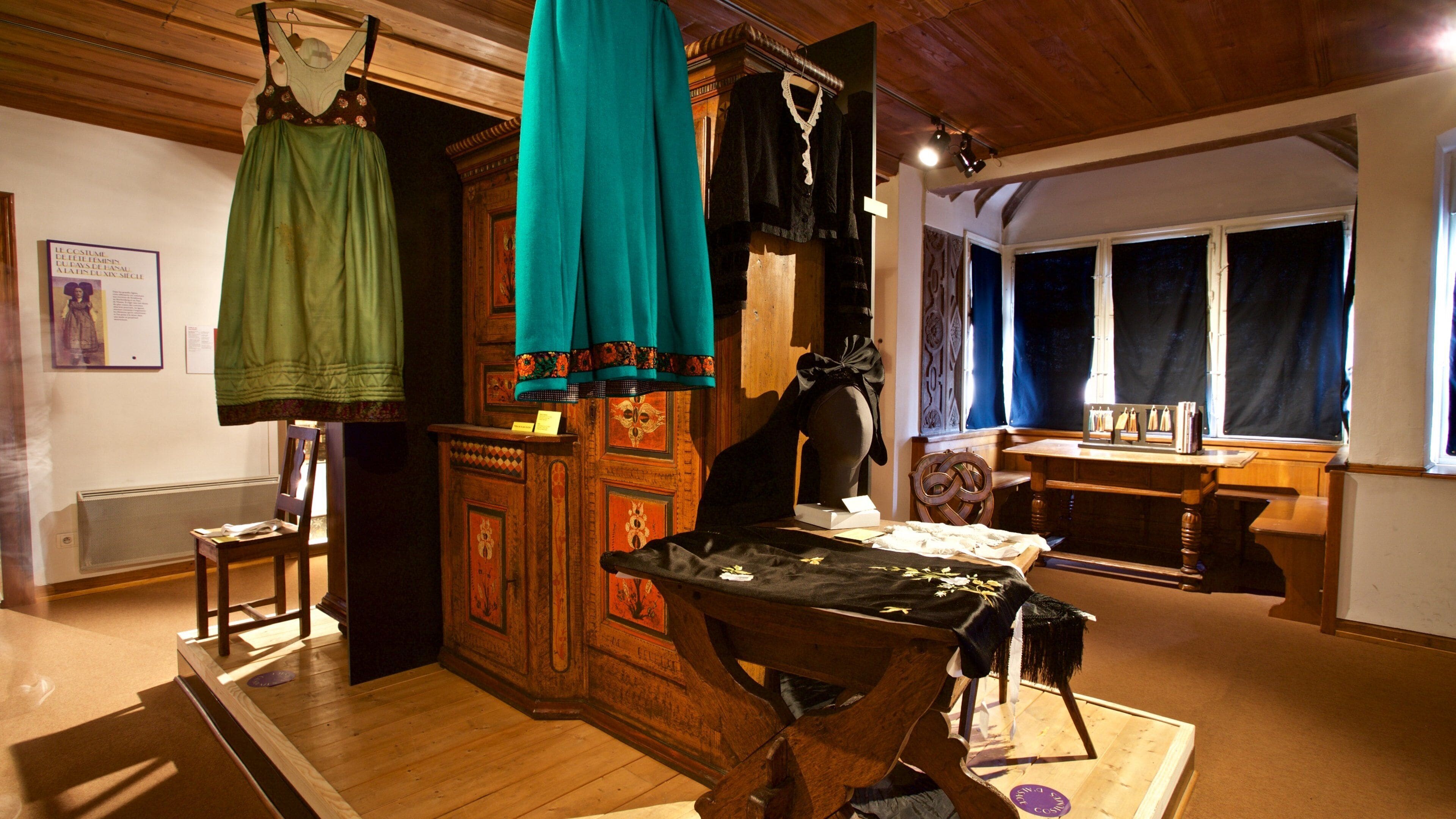 A room with a wooden cabinet, a mannequin, and various garments displayed on hangers.