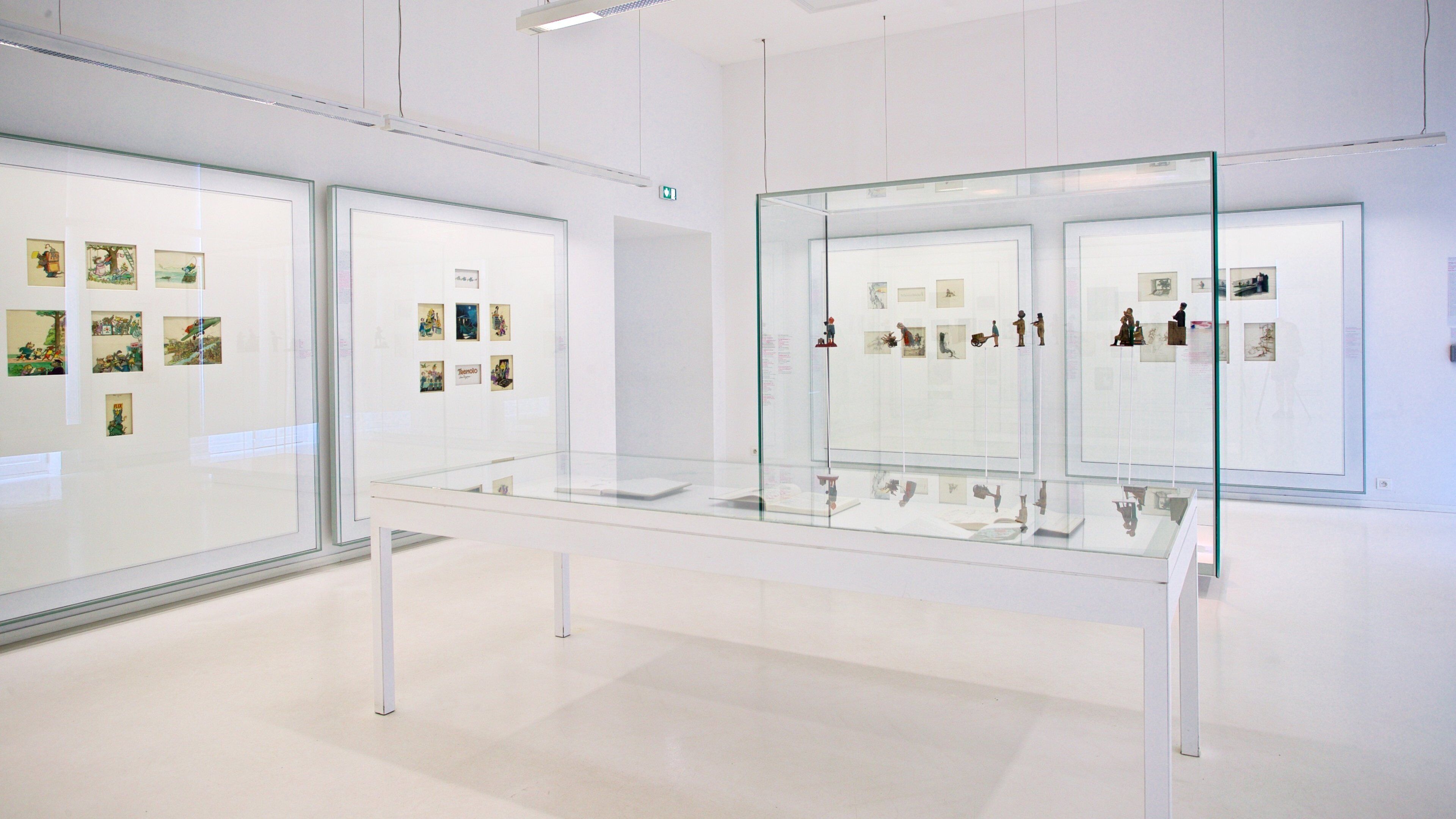 An art gallery with glass display cases containing various artworks.