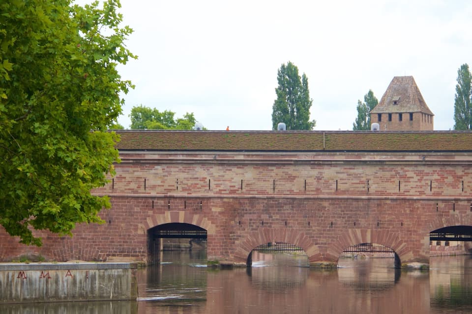A brick bridge over a canal with a tree in the foreground.
