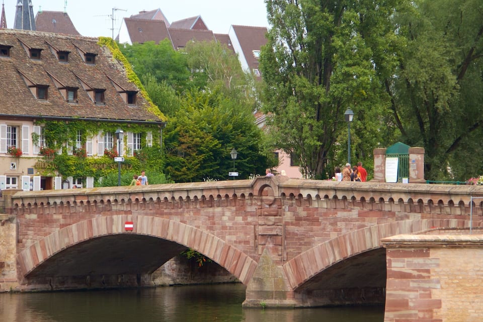 A stone bridge over a river with buildings and trees in the background.