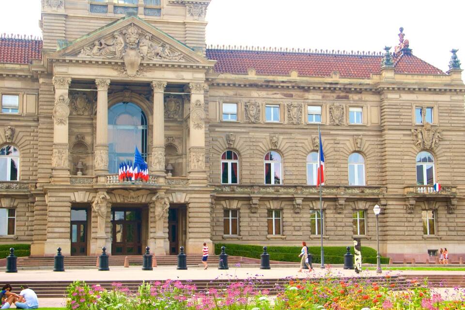 Un edifici històric amb arquitectura ornamentada, grans finestres i una bandera.