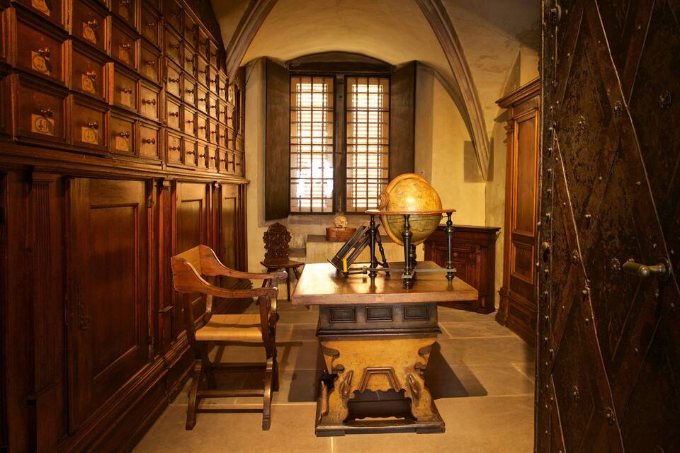 Une salle d’étude avec des armoires en bois, un globe terrestre et un bureau.