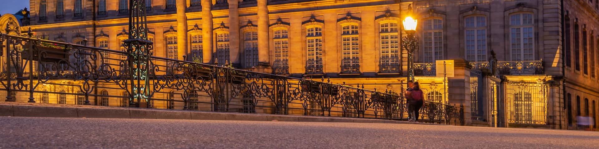 A historic building with ornate architecture and a prominent tower, illuminated by warm lighting.