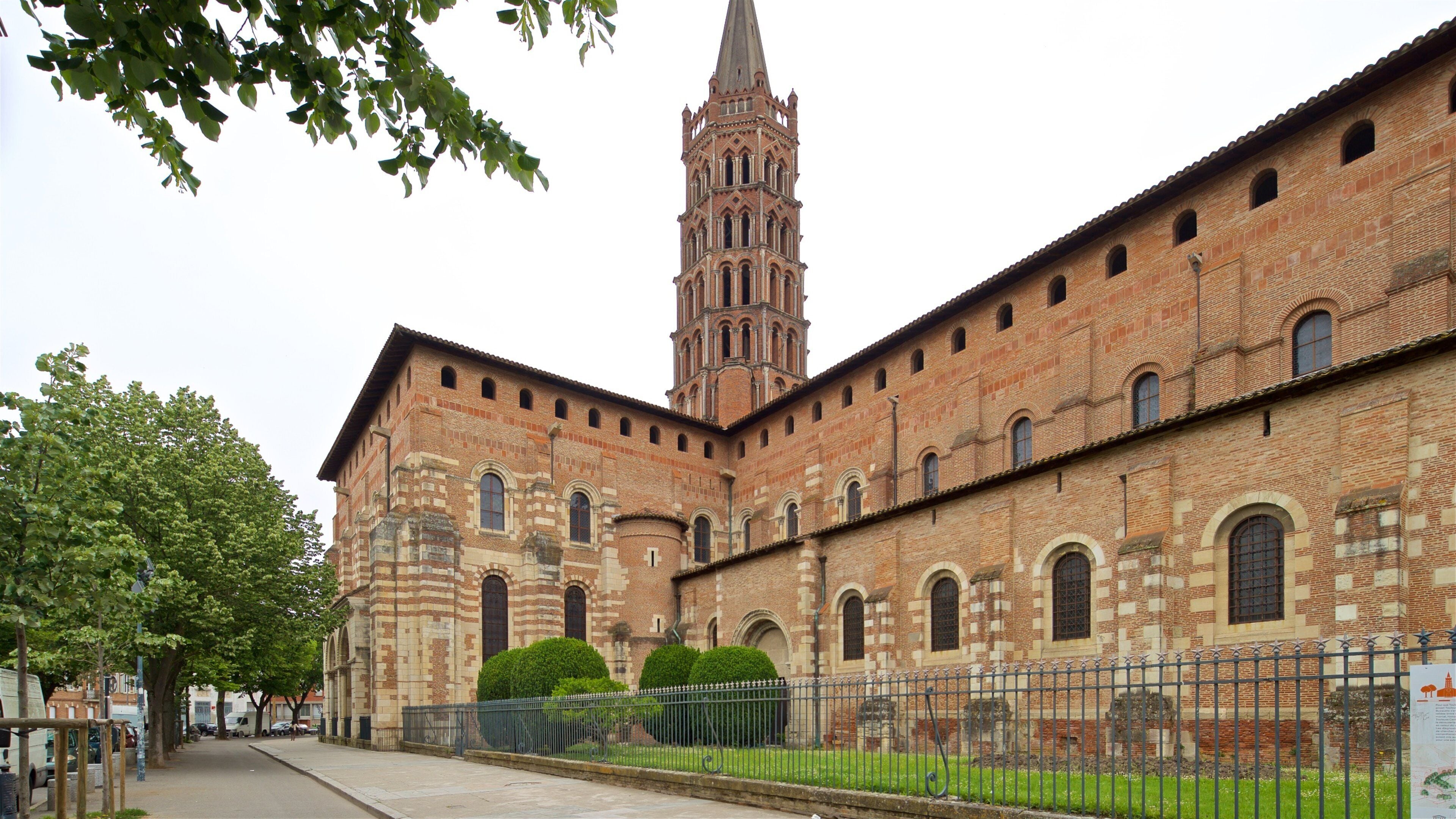 A historic brick building with a tall tower and arched windows.
