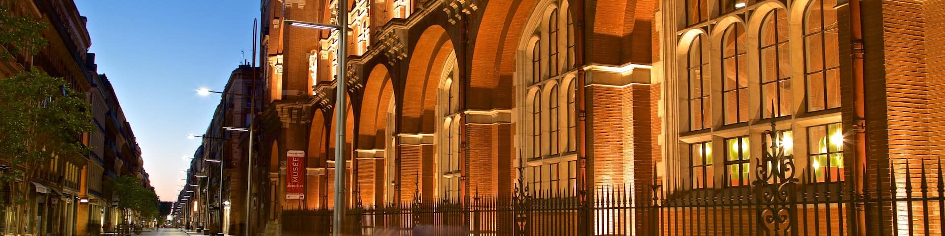 A street with a historic building featuring arched windows and brick architecture.