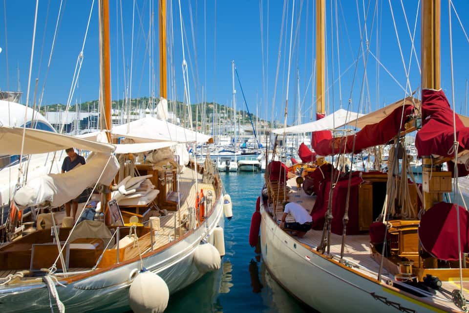 Een jachthaven met verschillende zeilboten afgemeerd, houten dekken en masten.