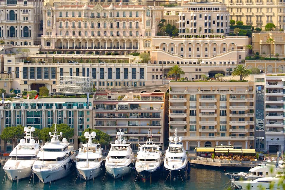 A marina with several yachts docked, surrounded by historic buildings with classical architecture.