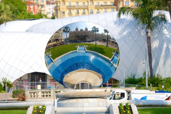 Un miroir sphérique qui reflète un bâtiment, des palmiers et une fontaine.
