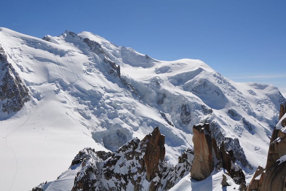 Une chaîne de montagnes enneigées, aux pics acérés et aux affleurements rocheux.