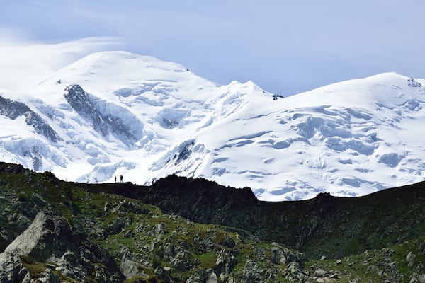 Une chaîne de montagnes enneigée, parsemée de rochers et de quelques zones de végétation.
