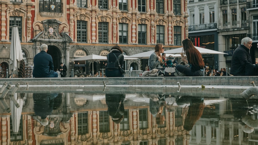 Lille Grand Square featuring a fountain and street scenes as well as a small group of people