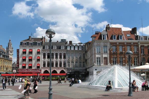 A bustling square with historic buildings, a fountain, and people walking around.