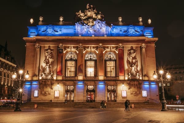 Un magnifique bâtiment illuminé, orné de statues et présentant une architecture riche et élaborée, de nuit.