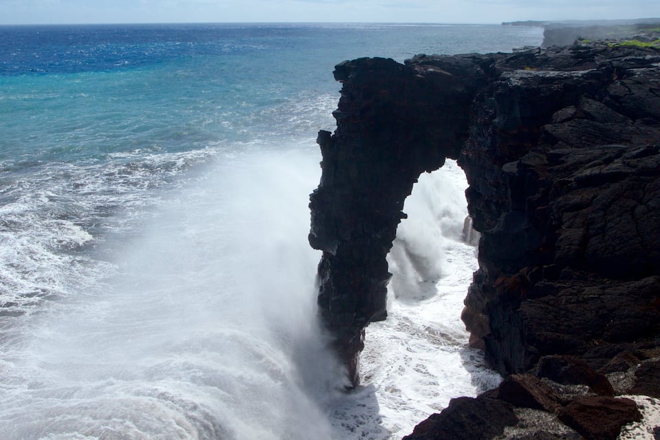 A coastal rock formation with a narrow passage through it, overlooking the ocean.