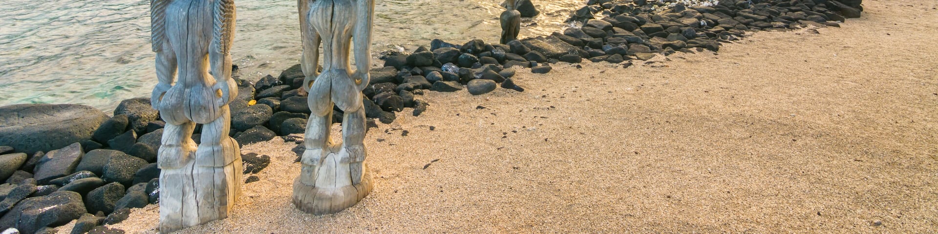 Una playa con palmeras, costa rocosa y un atardecer.