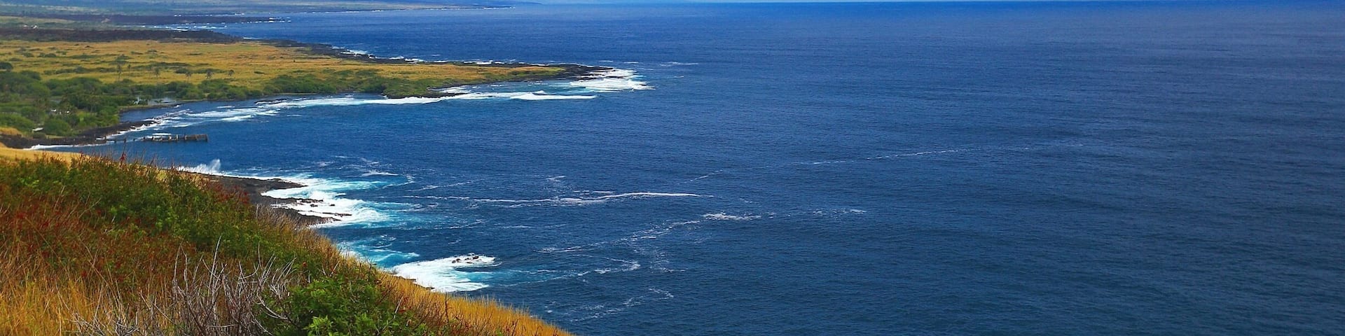The beautiful Pacific Ocean just around the bend at South Point At Big Island, Hawaii. Blue skies, bluer waters and green green grass! Beautiful!