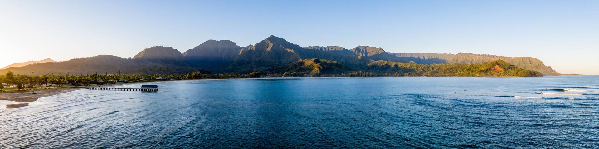 Aerial panoramic image at sunrise off the coast over Hanalei Bay and pier on Hawaiian island of Kauai
