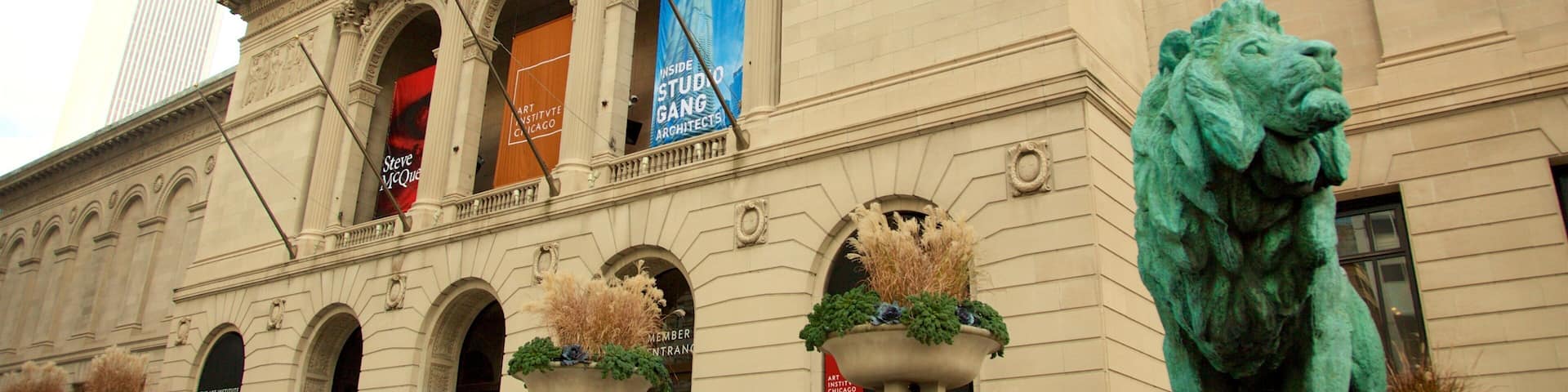 El edificio del Instituto de Arte de Chicago con arquitectura clásica, una estatua de león y pancartas anunciando eventos.