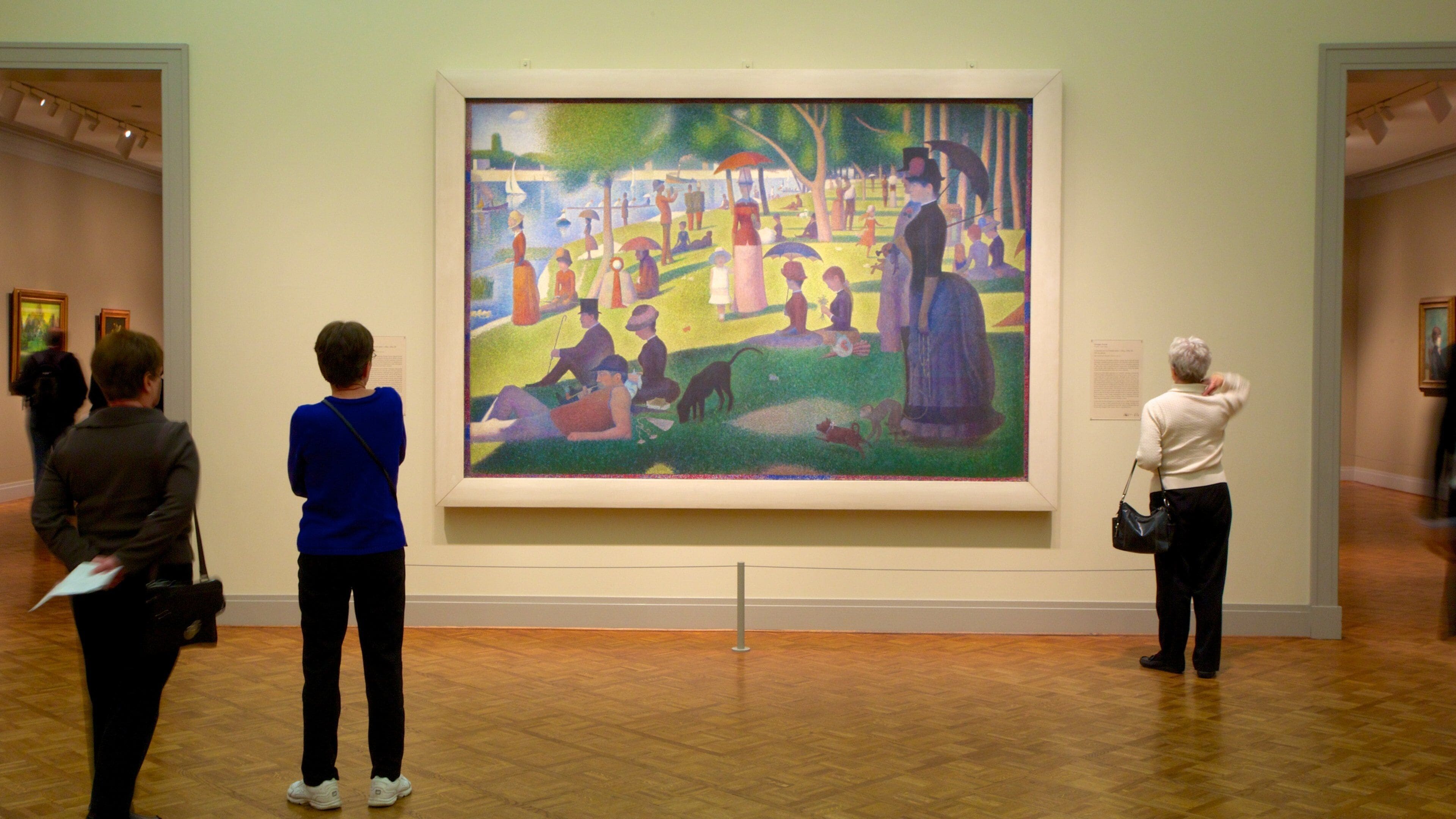 Un grand tableau représentant une scène de parc avec des personnes et un chien.