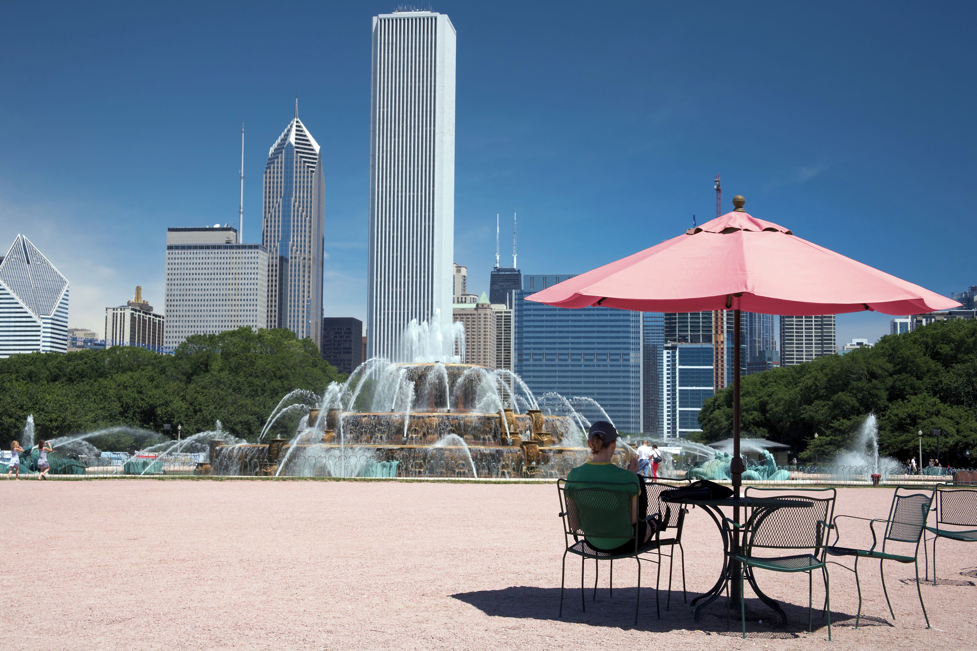 Girl sitting in the shade of a cafe umbrella near Chicago's Buckingham fountain
