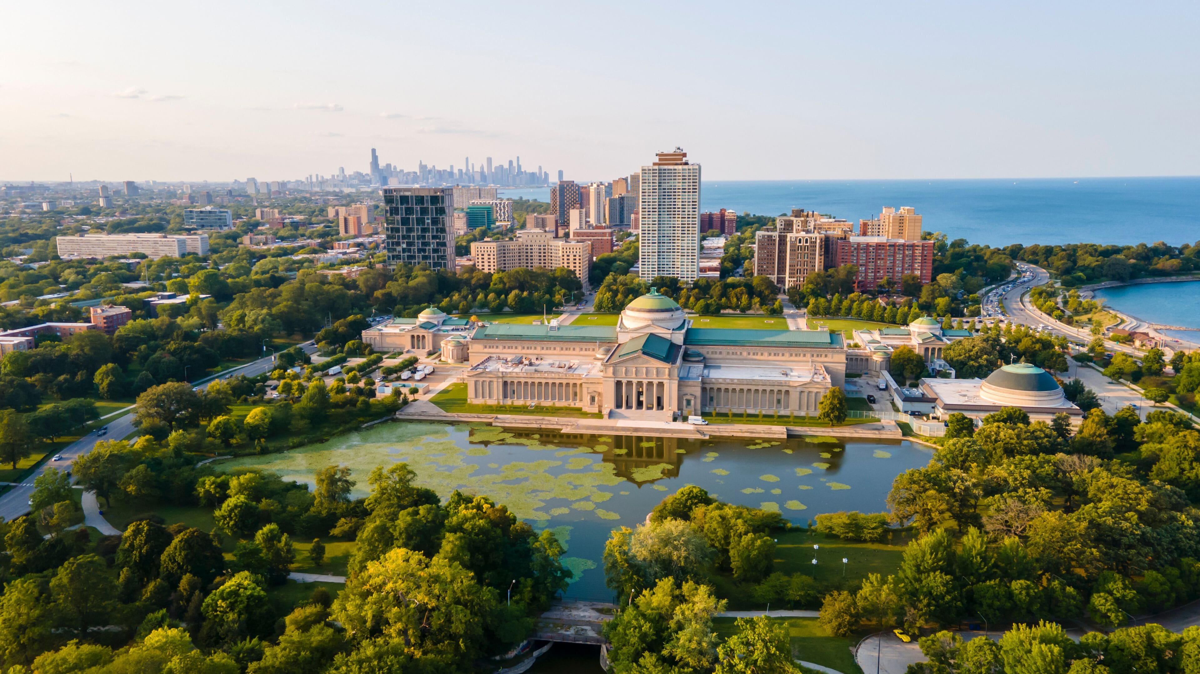 A cityscape with a prominent historical building surrounded by water, a dense urban area, and a distant skyline.