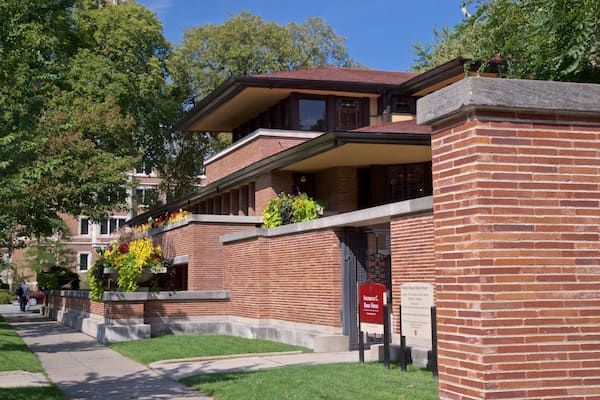A brick building with a red sign, green trees, and a clear sky.