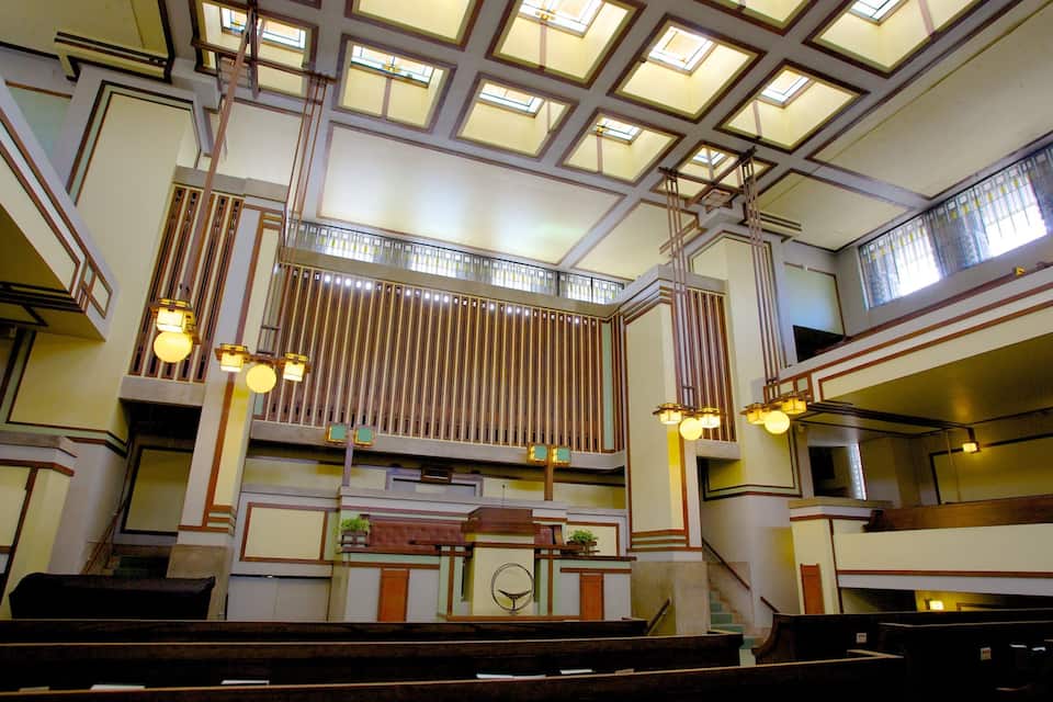 A church interior with a high ceiling, stained glass windows, and wooden pews.