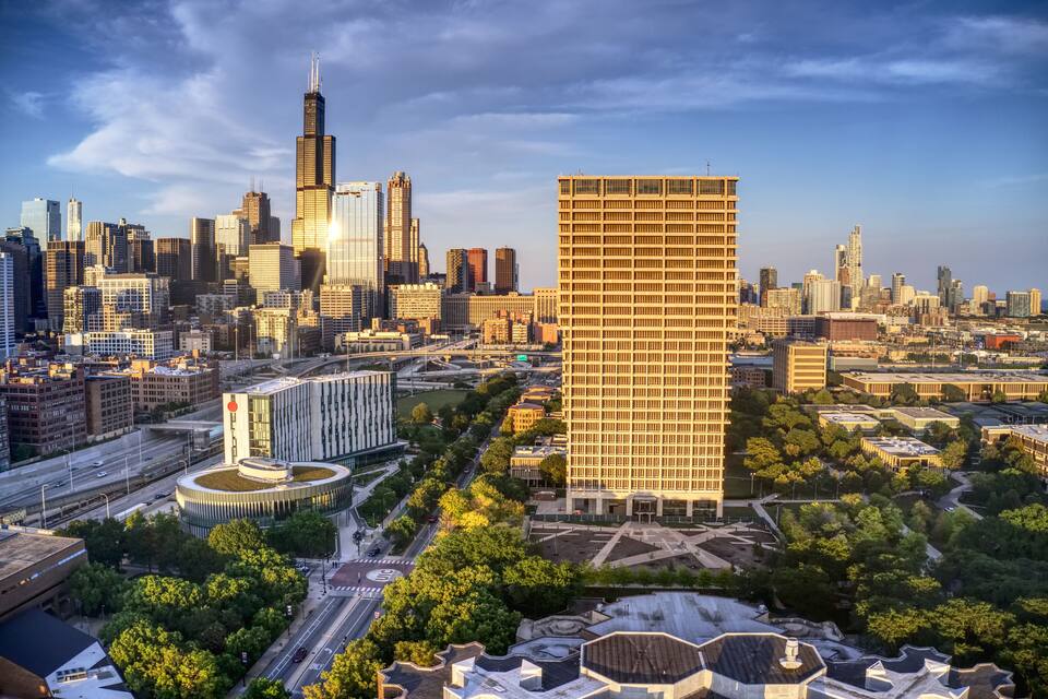 A cityscape with a prominent skyscraper, a circular building, and a large rectangular building.