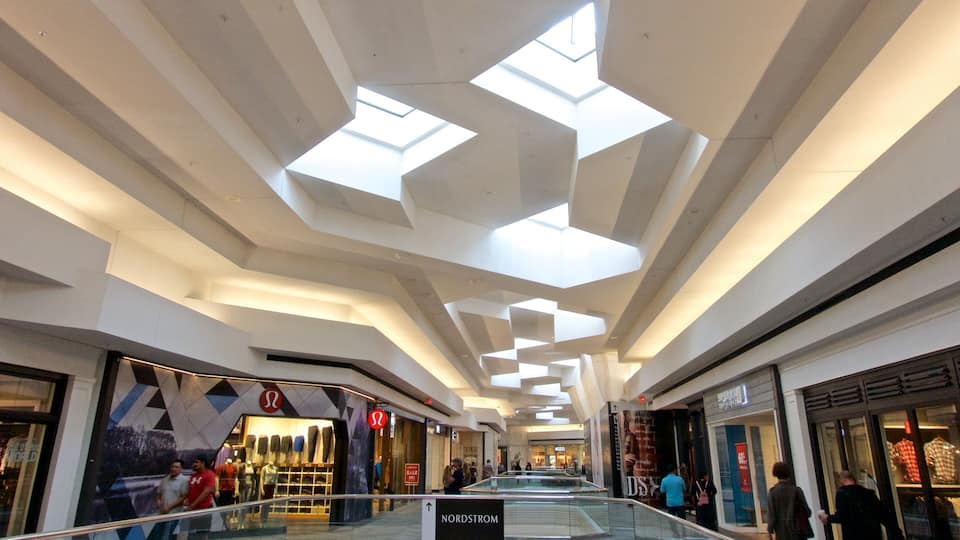 A shopping mall interior with a modern ceiling design and glass railings.