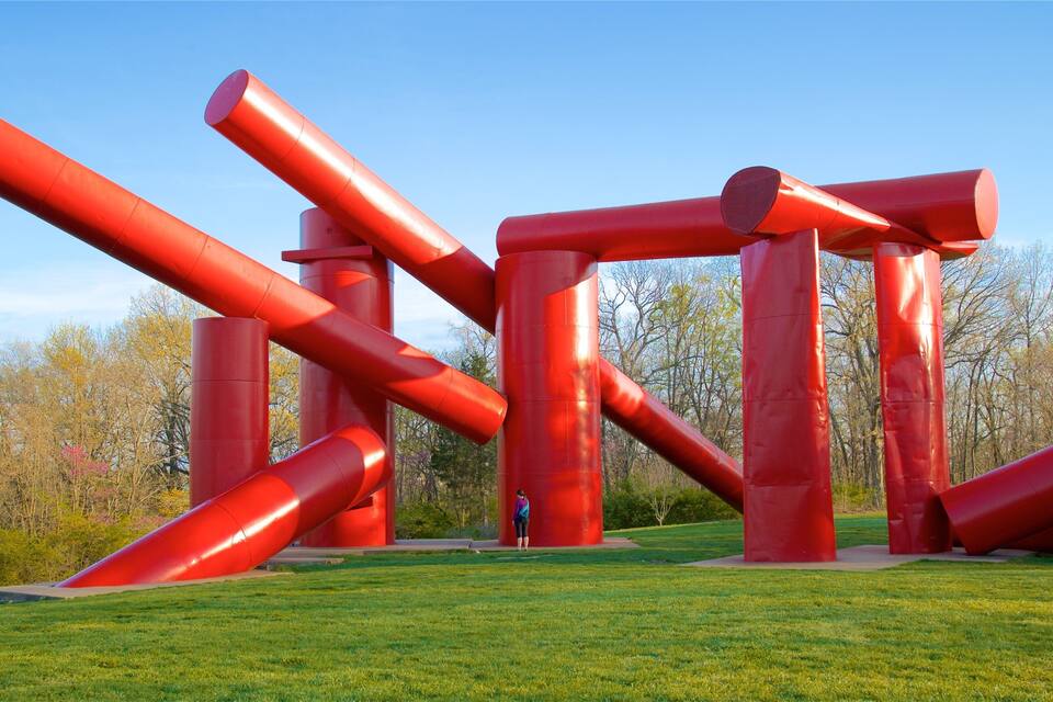 Escultura de estruturas metálicas vermelhas em um campo aberto.