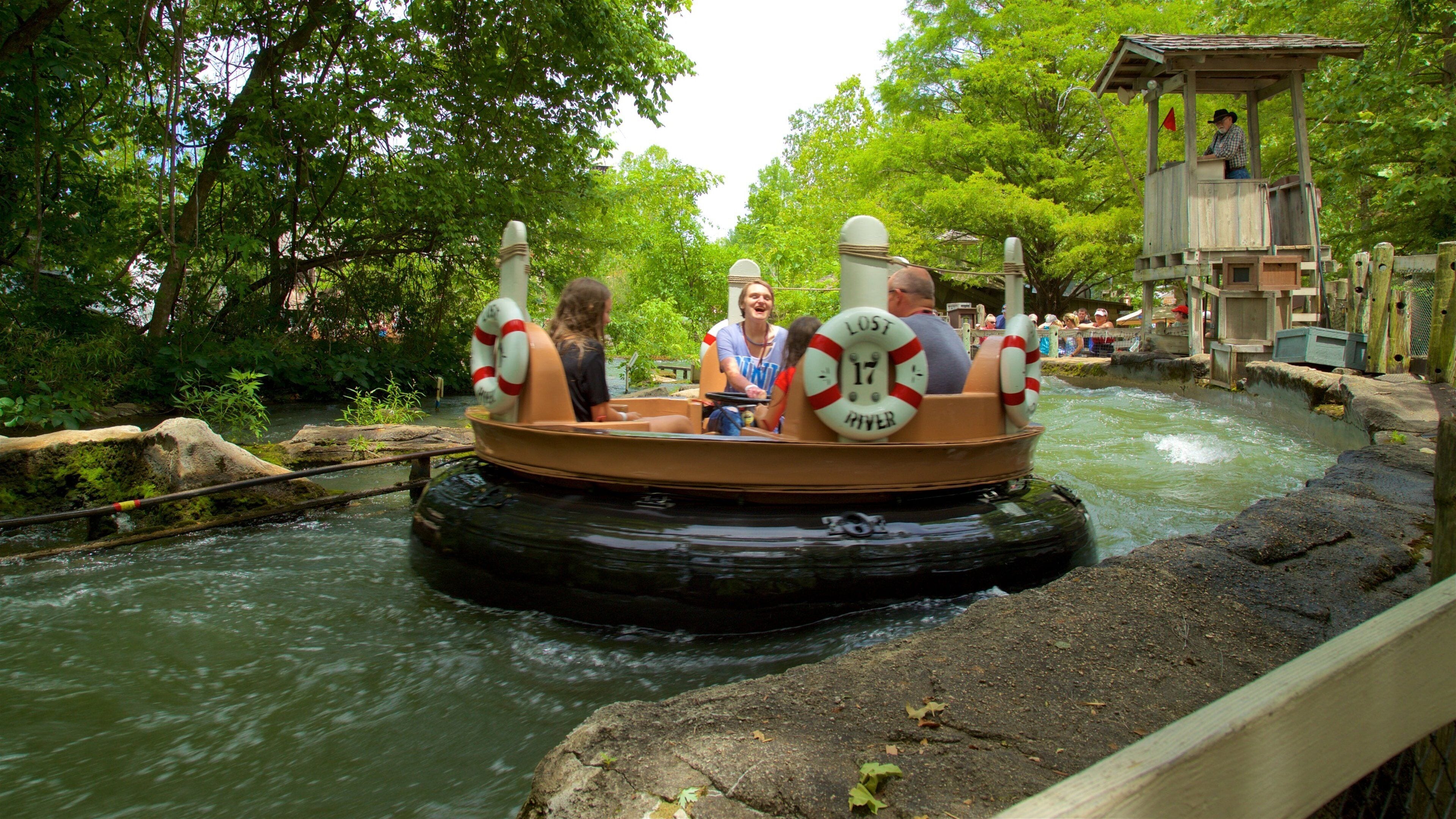 A river ride with a wooden raft, surrounded by lush greenery and a wooden observation tower.