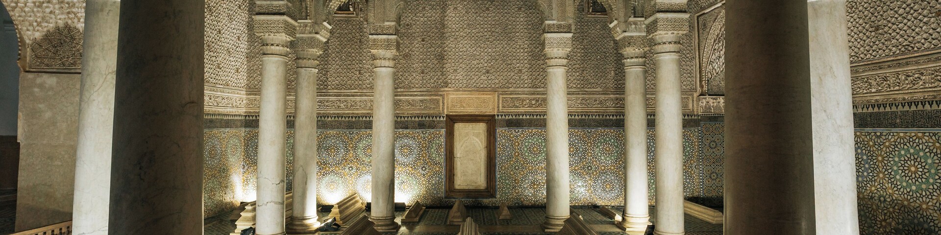 Un interior con columnas ornamentadas, detalles de azulejos intrincados y un arco central.