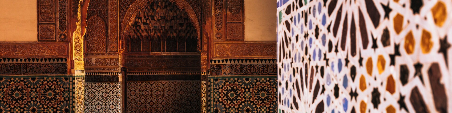 Un arco ornamentado con detallada labor de azulejos y un muro con motivos.