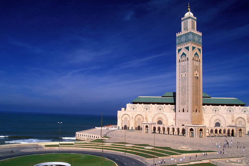 The Hassan II Mosque with a minaret, a large courtyard, and the Atlantic Ocean in the background.