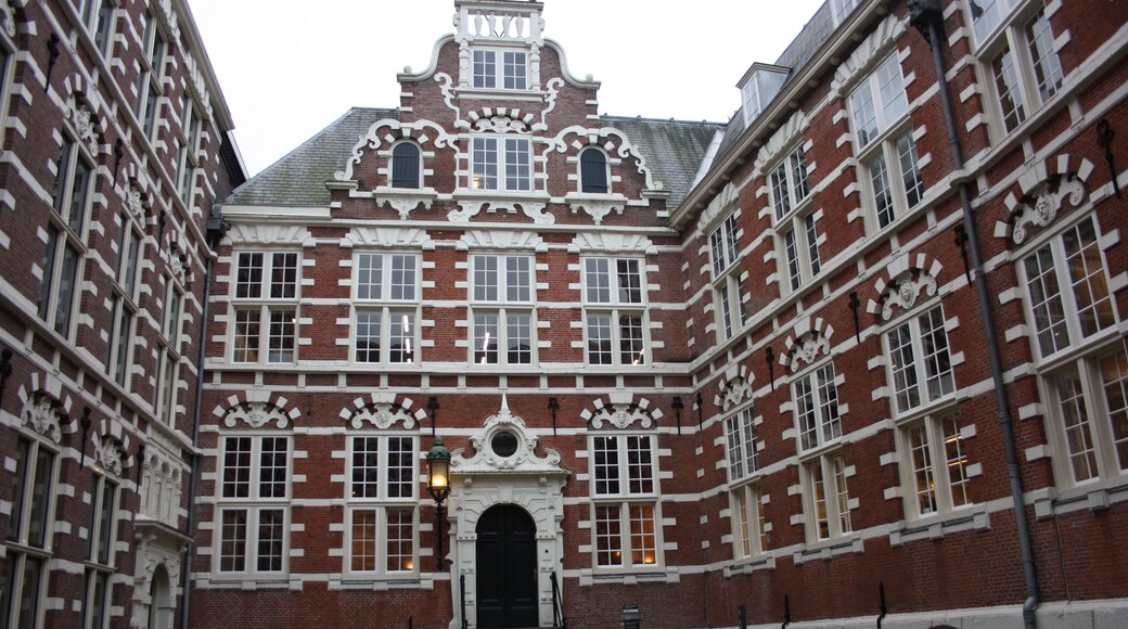 traditional inner courtyard surrounded by tall and old red brick walls. old building, vintage Dutch style. fascinating amsterdam building used as a university