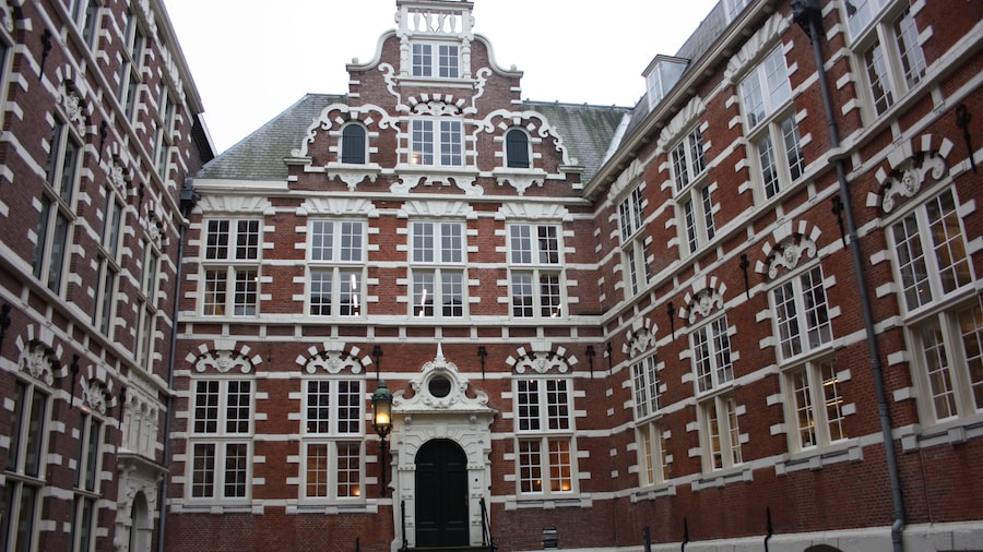 traditional inner courtyard surrounded by tall and old red brick walls. old building, vintage Dutch style. fascinating amsterdam building used as a university