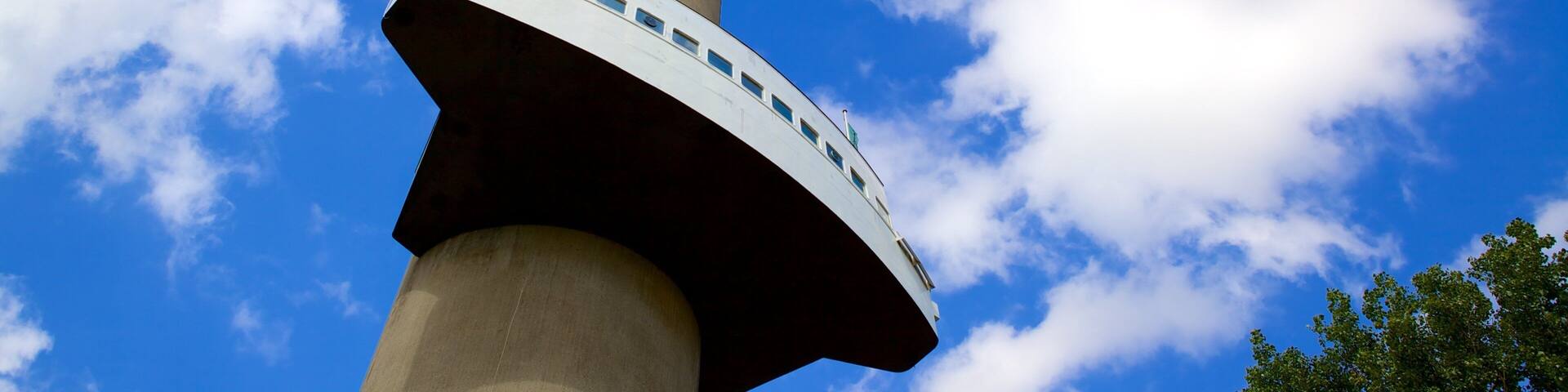 A tower with a circular observation deck against a blue sky with clouds.