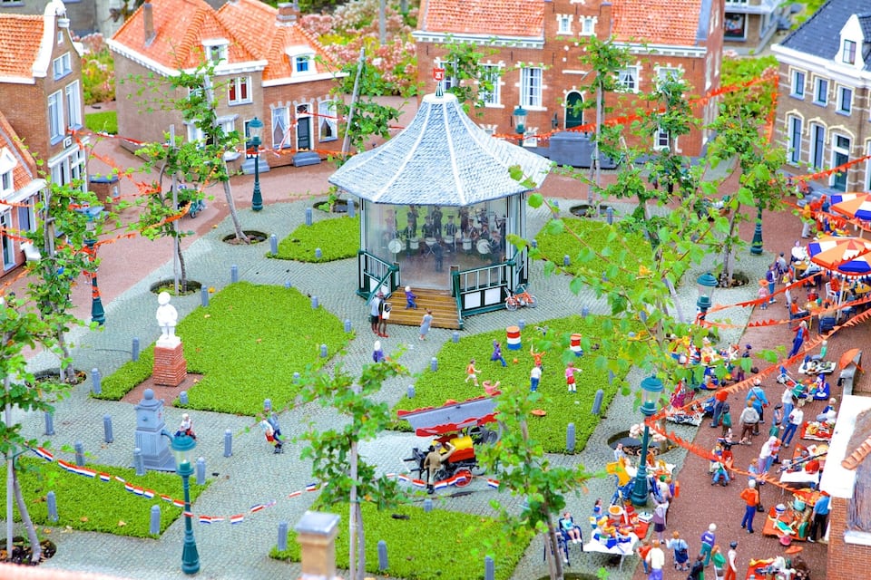 Uma maquete de uma praça europeia, com um coreto, estátuas e figuras em miniatura.