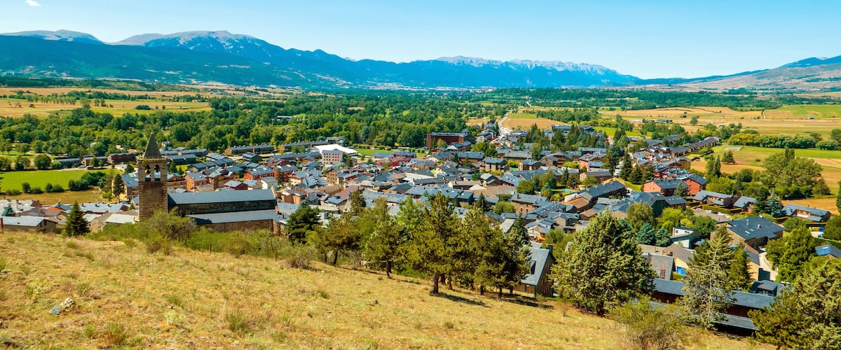 A town nestled in a valley with mountains in the background.