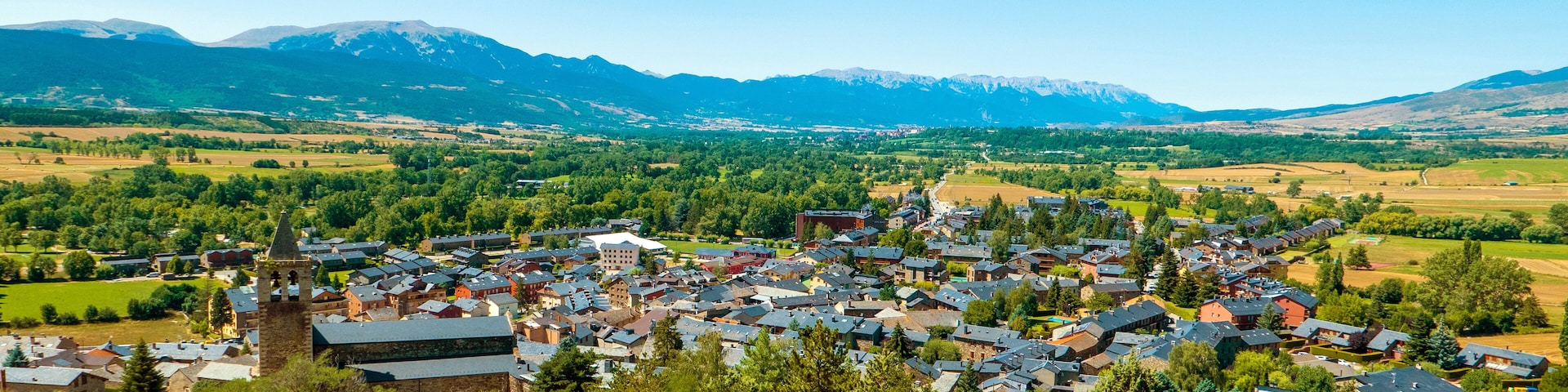 A town nestled in a valley with mountains in the background.