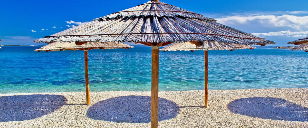 Pebble beach and turquoise sea umbrella, Zrce beach, Island of Pag, Croatia