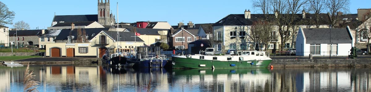 Une rivière paisible où l’on peut apercevoir des bateaux, une église et des maisons le long des rives.