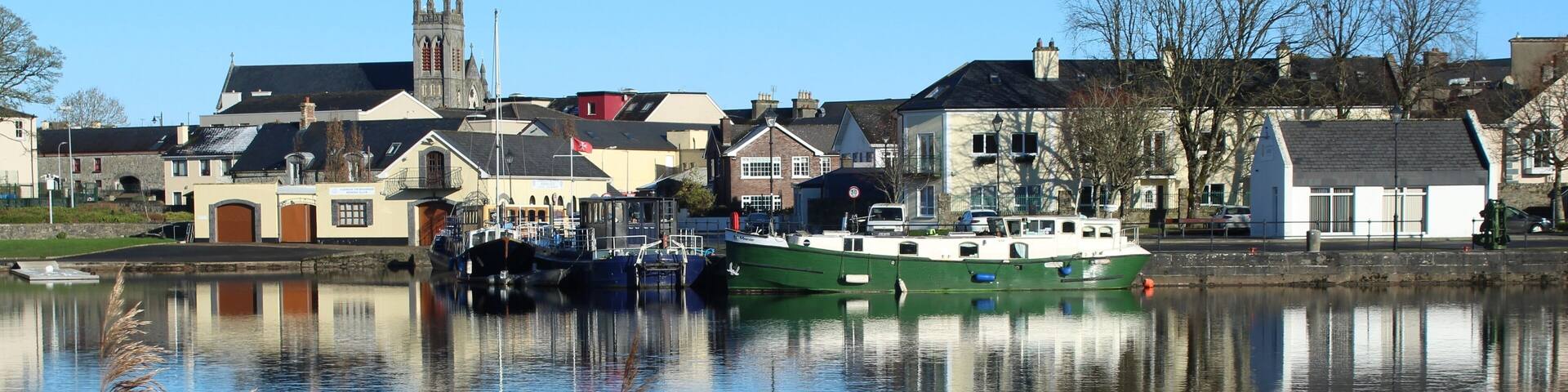 A calm river with boats, a church, and houses along the banks.