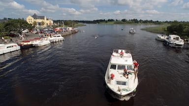 A river with boats docked along the banks, a building in the background, and a clear sky.